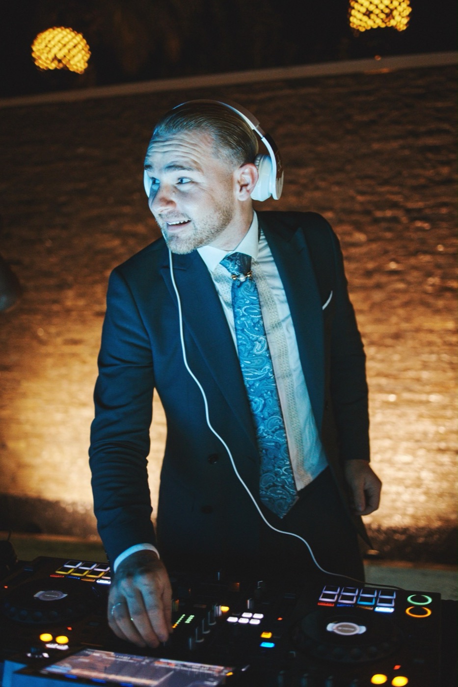 DJ in abito elegante con le cuffie alla consolle