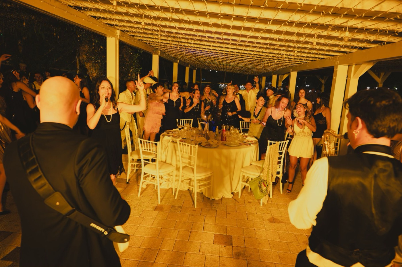 Festa a tema anni '20: la cantante canta tra gli ospiti in piedi attorno al tavolo