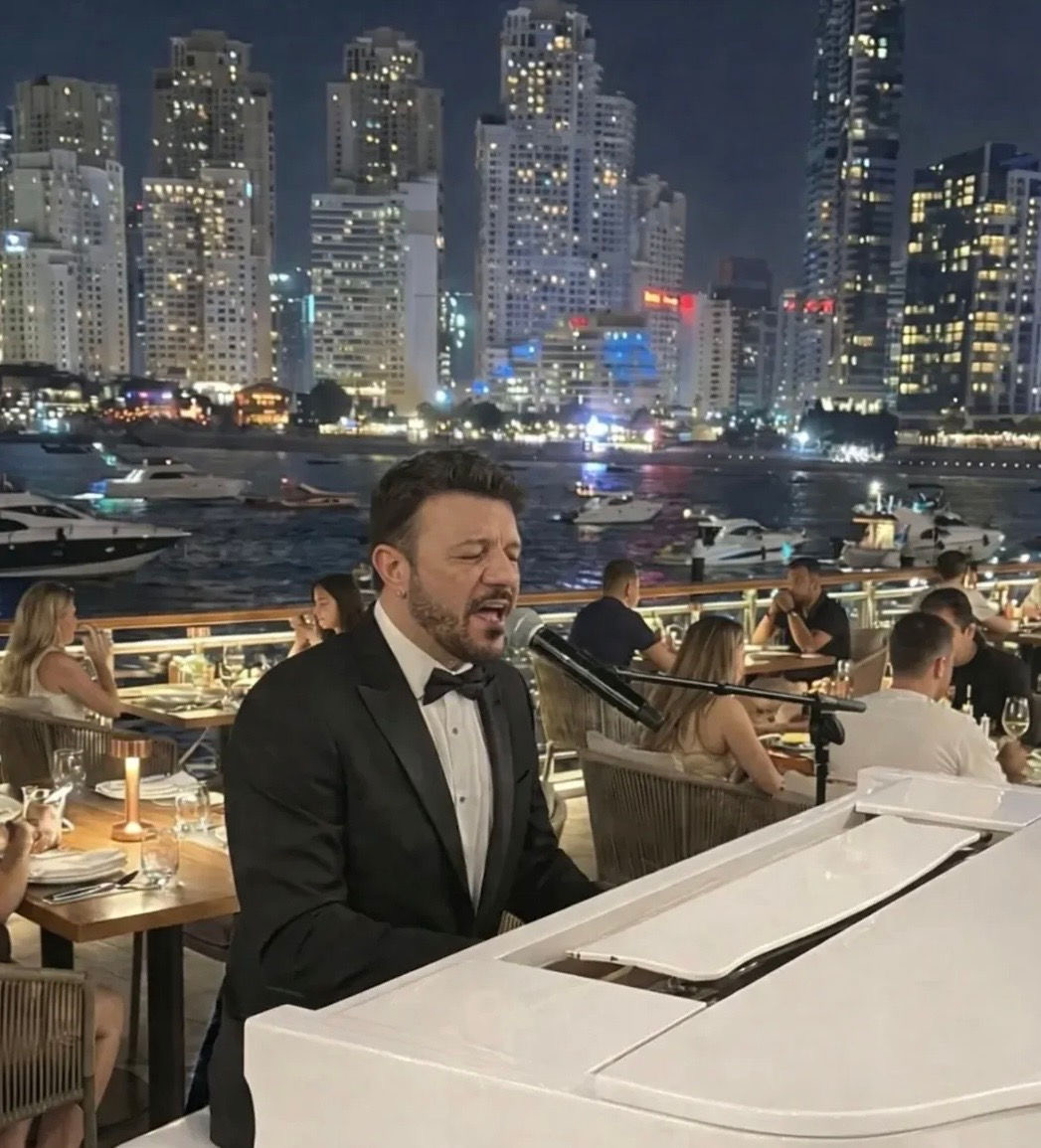 Pianista in smoking al pianoforte bianco con skyline notturno