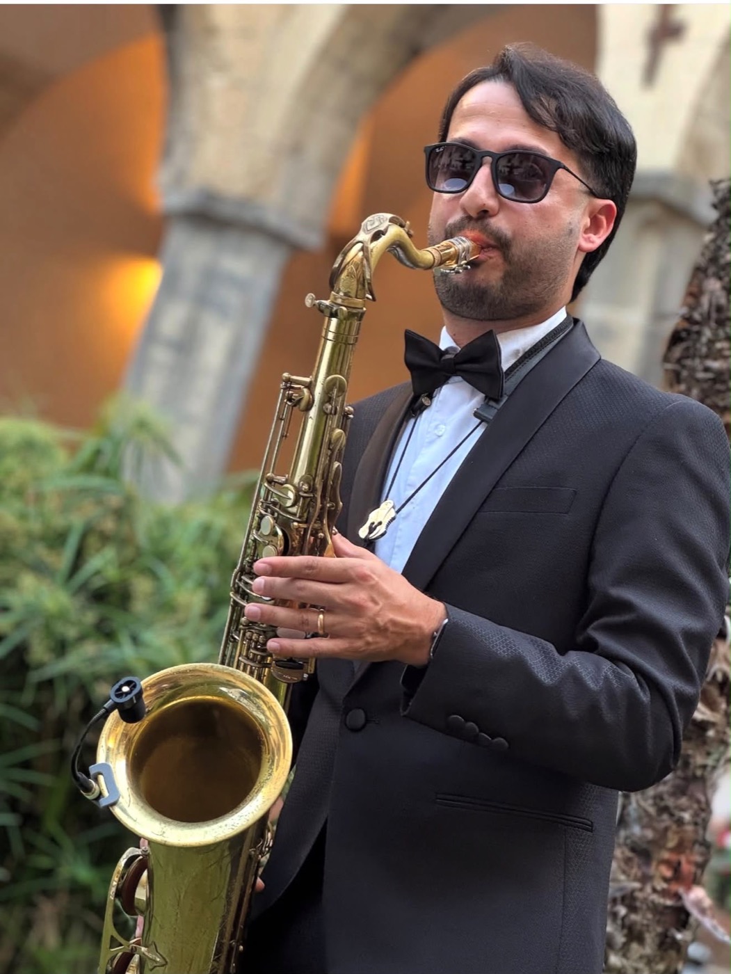 Sassofonista in smoking suona in un chiostro durante un evento