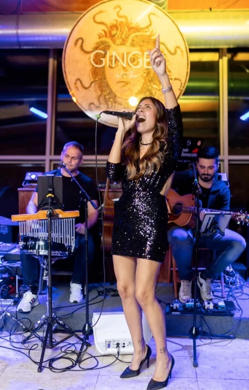 Cantante con trio acustico, chitarra e percussioni, durante una serata live